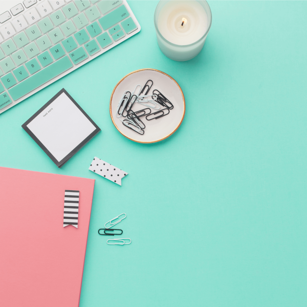 teal desk with keyboard and pink notebook