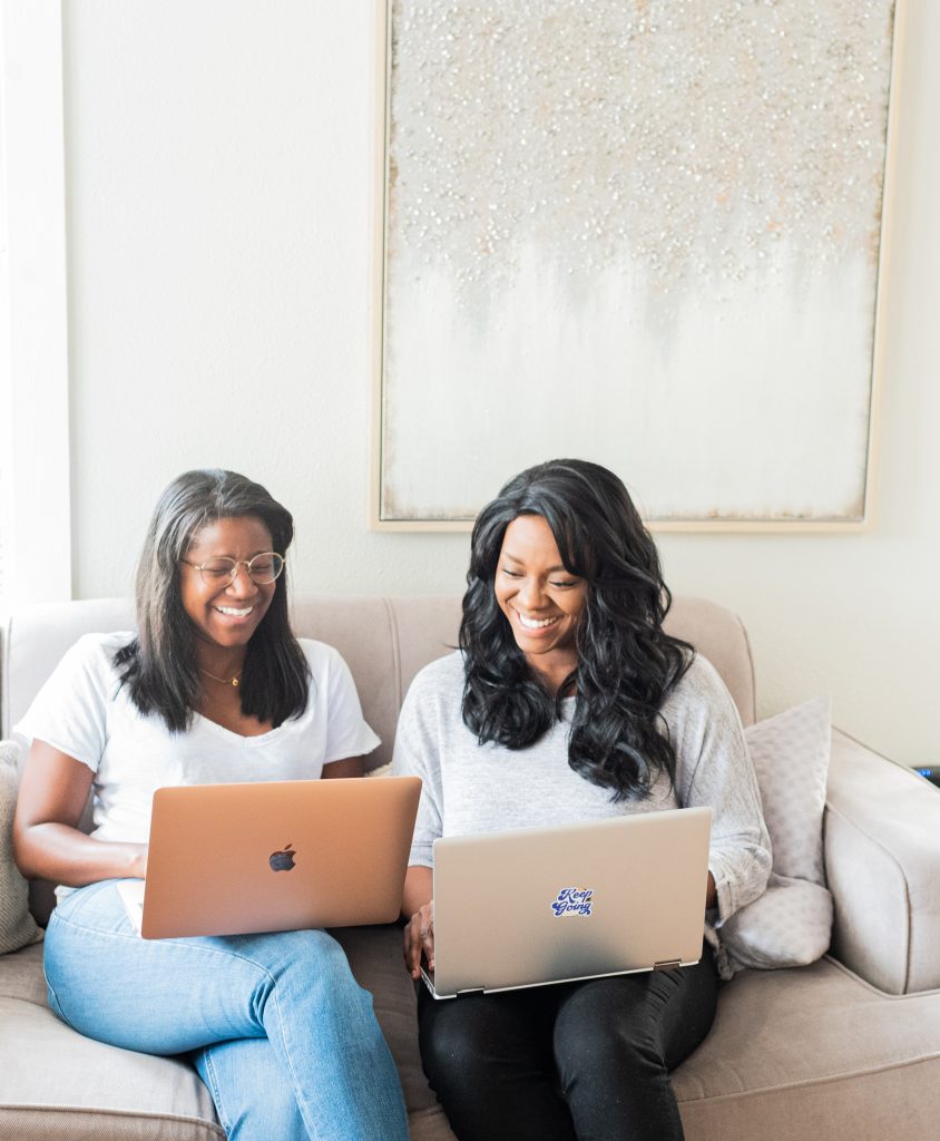 2 girls working on laptops on the couch