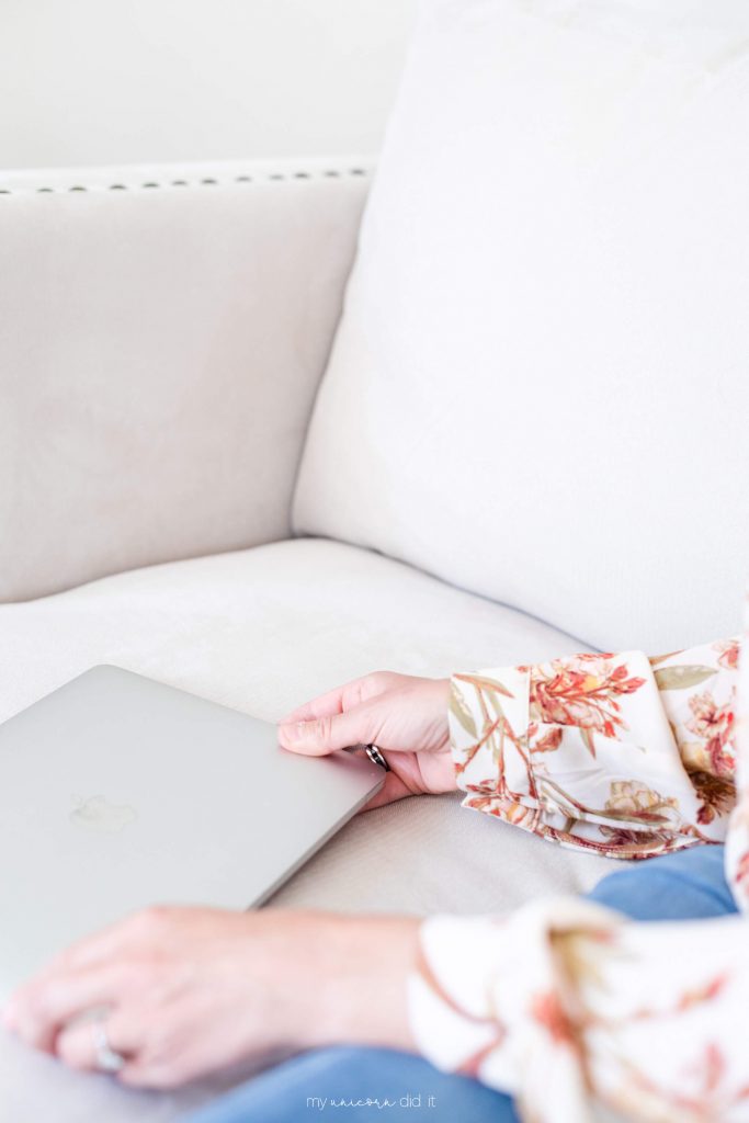 girl with floral long sleeve top on couch with macbook