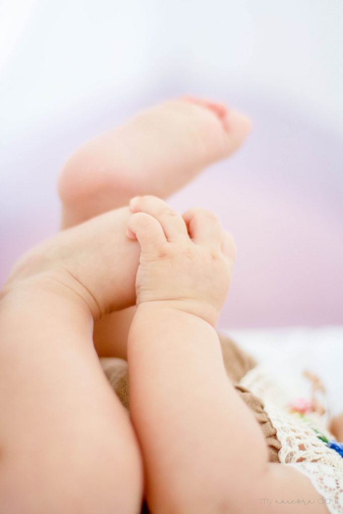 infant girl holding her feet