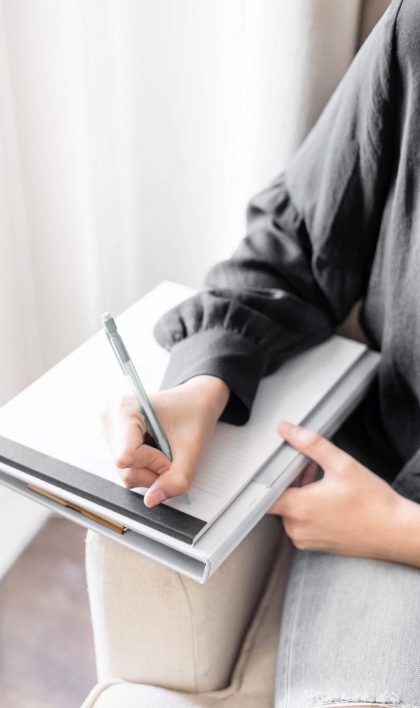 girl with long sleeve black shirt writing on notepad